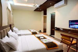 a hotel room with two beds and a television at Unnati Stay Inn in Bijāpur