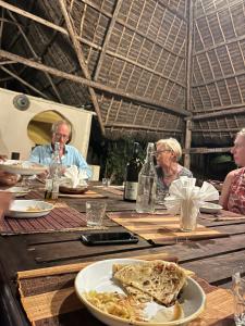 a group of people sitting at a table with a plate of food at Sazani Beach Lodge and Tidal Lounge in Nungwi