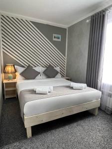 1 dormitorio con 1 cama con 2 toallas en Kausar Hotel en Bishkek