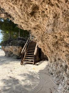 eine Treppe, die in eine Höhle in einer Felswand führt in der Unterkunft Sazani Beach Lodge and Tidal Lounge in Nungwi