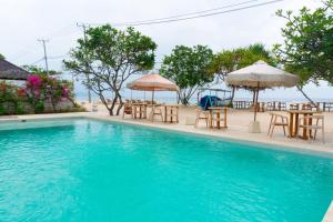 a swimming pool with tables and chairs and umbrellas at Ora Villas Gili Meno in Gili Meno