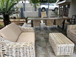 a patio with wicker furniture and a table and chairs at South Coast Suburban Escape in Kingsburgh