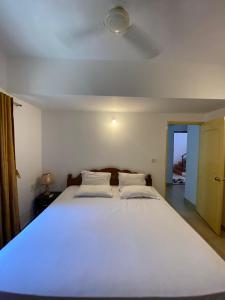 a bedroom with a large white bed with a ceiling at Apricot BH6 in Marmagao