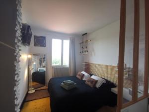 a bedroom with a bed with a blue blanket and a window at Maison du bonheur in Lanton