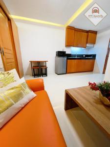 塔克洛班的住宿－GTC Apartelle，客厅配有橙色沙发和桌子