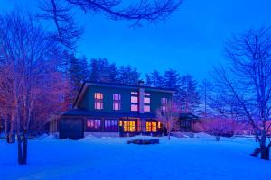 a house in the snow at night with pink lights at Powderhouse by The Hakuba Collection in Hakuba