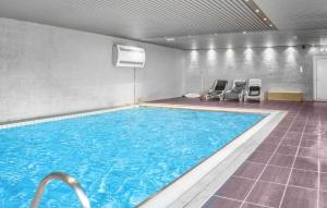 a large swimming pool with two chairs in a room at Nice Apartment In Vossestrand With Swimming Pool in Vossestrand