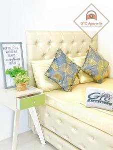 a couch with pillows and a table with a sign at GTC Apartelle in Tacloban