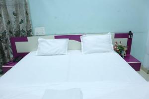 a white bed with two pillows on top of it at Radhe Radhe Guest House in Dehradun