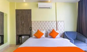 een slaapkamer met een bed met oranje kussens en een blauwe stoel bij FabHotel Aspiring Inn in Calcutta