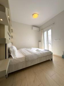 ein weißes Schlafzimmer mit einem großen Bett und einem Fenster in der Unterkunft Gtrip Alimos Brand New Apt - 3059 in Athen