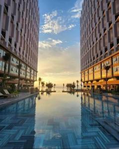 uma grande piscina entre dois edifícios altos em PEARL APEC MANDALA em Mui Ne