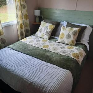 een slaapkamer met een bed met kussens en een raam bij Beautiful 3 bedroom caravan with hot tub - Tattershall Lakes in Tattershall