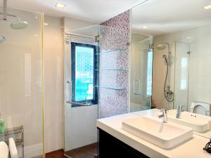 a white bathroom with a sink and a shower at Grand Diamond Condominium in Bangkok