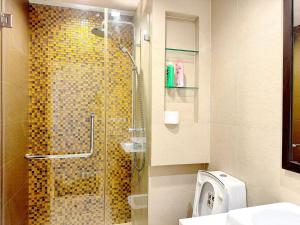 a bathroom with a shower with a glass door at Grand Diamond Condominium in Bangkok