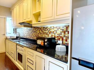 a kitchen with white cabinets and a black counter top at Grand Diamond Condominium in Bangkok