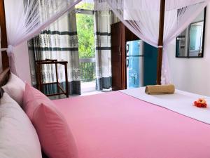 Cama rosa en habitación con ventana en Era Holiday House en Mirissa