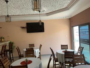 a dining room with two tables and a tv on the wall at JUBILEE EXECUTIVE LODGE in Lusaka