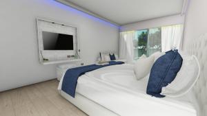 特拉加基的住宿－Magique Bleu Suites，白色的卧室设有一张大床和一个窗户