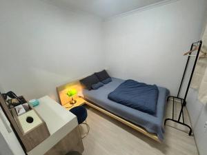 Habitación pequeña con cama y escritorio. en Homey inn Juno, en Suwon