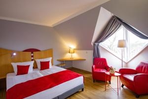 ein Hotelzimmer mit einem Bett und einem roten Stuhl in der Unterkunft Inselhotel kleiner Bodden in Buschvitz