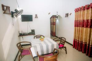 a room with a table and chairs and a television at Sajini Villa in Weligama