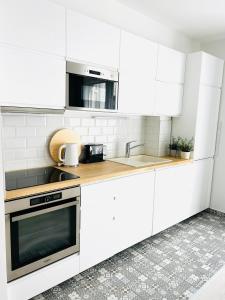 Biała kuchnia z białymi szafkami i zlewem w obiekcie Elizabeth Garden Premium Apartment w mieście Kecskemét