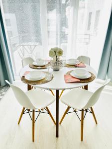 a dining room table with white chairs and a white table and chairs at Elizabeth Garden Premium Apartment in Kecskemét