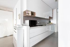 La cuisine est équipée de placards blancs et d'un four micro-ondes. dans l'établissement Bright Apartment with balcony and terrace, à Milan