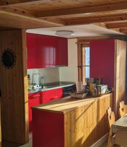 cocina con armarios rojos y encimera en Mimöseli en Schwarzsee