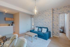 een woonkamer met een blauwe bank en een tafel bij Le Cabourgeais centre ville in Cabourg