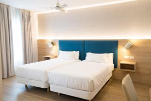 two beds in a hotel room with a blue headboard at Hotel Parking Miradoiro de Belvís in Santiago de Compostela