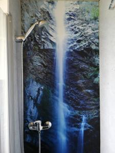 eine Dusche mit einem Wasserfall-Gemälde an einem Fenster in der Unterkunft Ferienwohnung Gruberhörndlblick in Inzell