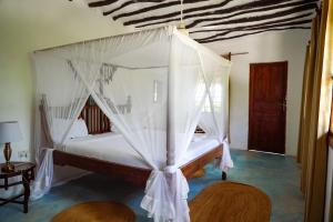 a bedroom with a bed with a canopy at Makuti Beach Bungalows in Bwejuu