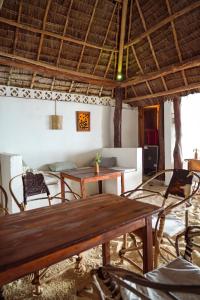 a dining room with a wooden table and chairs at Makuti Beach Bungalows in Bwejuu