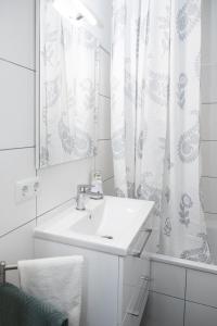 uma casa de banho branca com um lavatório e um espelho em Schöne Wohnung am See mit Wi-Fi & Netflix em Bielefeld