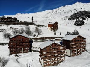 a group of buildings in the snow next to a mountain at Résidence Courmayeur - 2 Pièces pour 6 Personnes 874 in Les Menuires