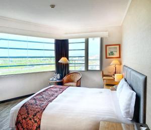 a hotel room with a bed and a large window at Golden Tulip Zhong Xin Hotel Taichung in Taichung