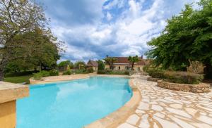 een zwembad in een tuin met een huis bij Hôtel de la Ferme Lamy in Meyrals
