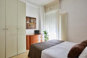 a bedroom with a bed and a dresser and a window at Residence Fellini in Rimini