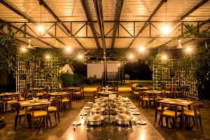 un comedor con mesas, sillas y luces en Dandeli Jungle Stay, en Dandeli