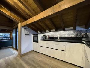 a kitchen with black counter tops and wooden ceilings at Chalet Des Encombres - Pièces 314 in Saint-Martin-de-Belleville
