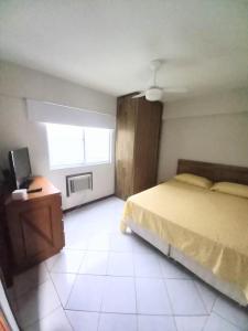 1 dormitorio con cama, escritorio y ventana en Apto 4 quartos em BC com garagem enorme, cabem 2 carros pequenos, en Balneário Camboriú