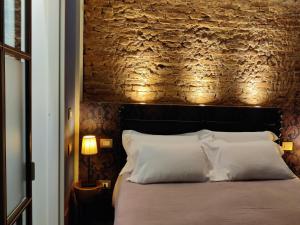 a bedroom with a brick wall and a bed with white pillows at Casa Sansera in Chioggia