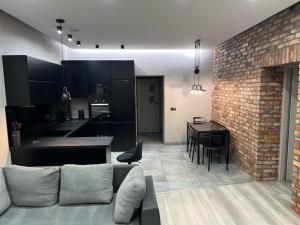 a living room and kitchen with a brick wall at Raciborska Royal Apartment - miejsce parkingowe na parkingu strzeżonym in Gliwice