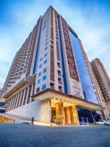 een hoog gebouw met blauwe ramen op een straat bij TIME Ruba Hotel & Suites in Mekka