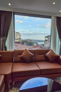 a couch in a living room with a large window at By Aydın Suites in Istanbul