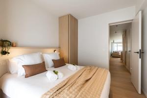 a bedroom with a large white bed with towels on it at Huswell - Central located apartment with parking in Knokke in Knokke-Heist