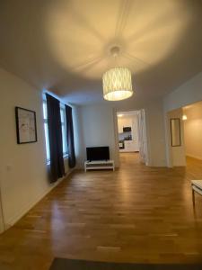 een lege woonkamer met een bank en een kroonluchter bij Elegant Apartment In The City in Göteborg