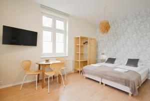 een slaapkamer met een bed en een tafel en stoelen bij Victus Apartamenty, Apartamenty Compassi in Sopot